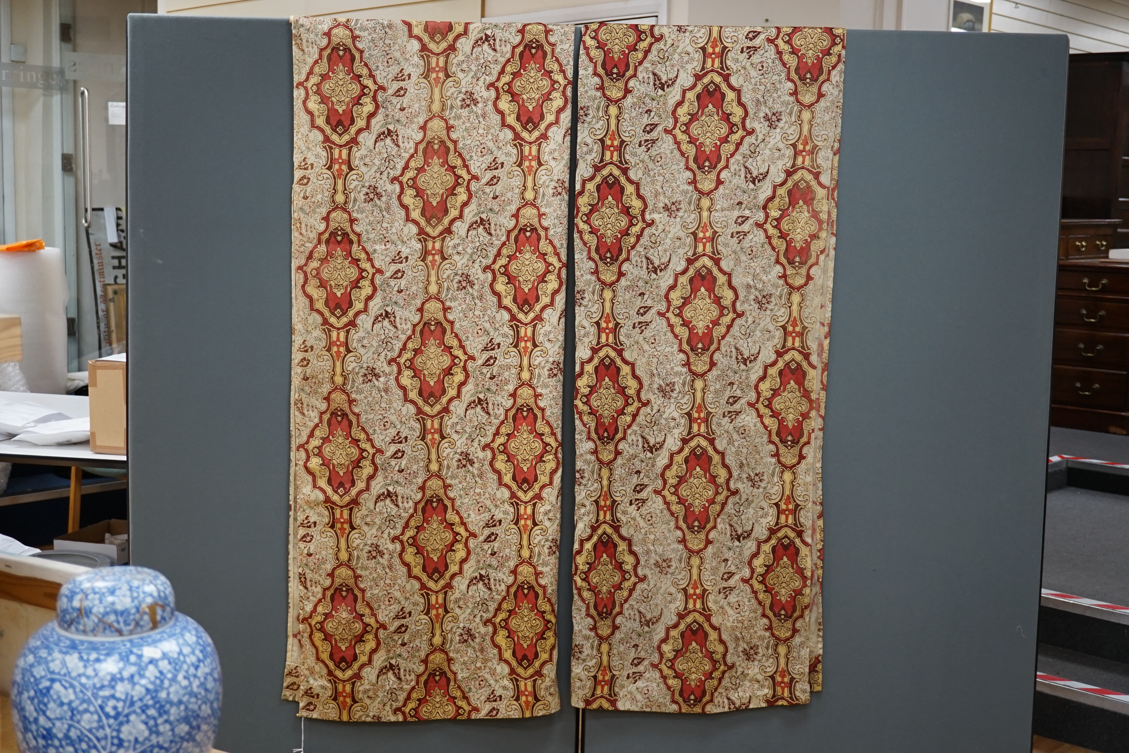 A pair of early 20th century block printed wool curtains, possibly French, made from two short looms (60cm each), printed in an ornate pattern in reds, ochres and greens, each curtain, 116cm wide x 208cm long. Condition